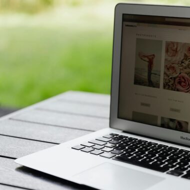 Close-up of an open laptop on a table displaying a website outdoors.