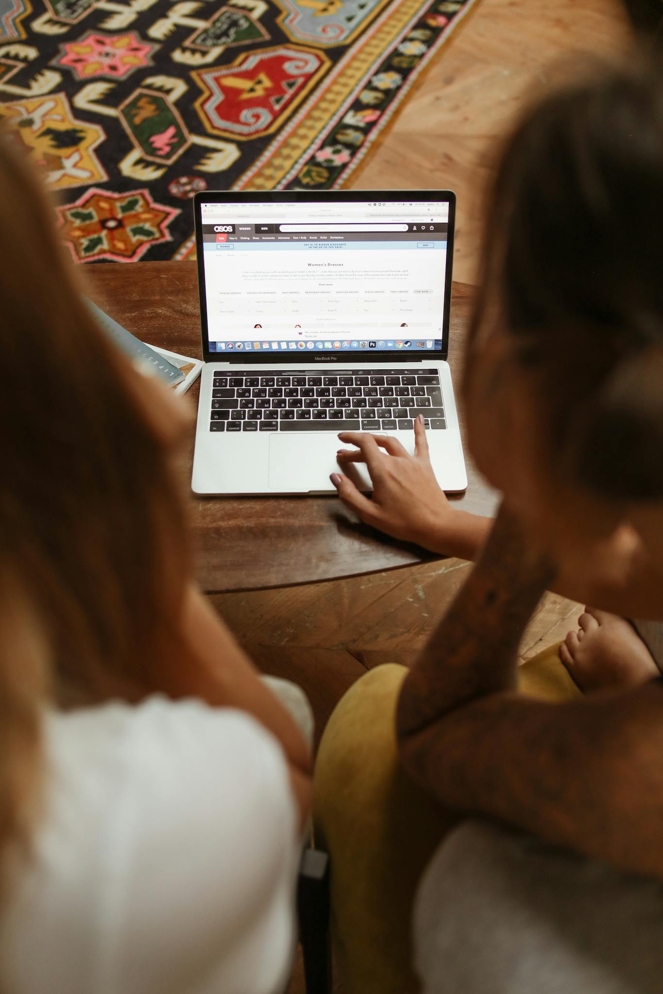 Two individuals browsing an online store together on a laptop, engaged in digital shopping.